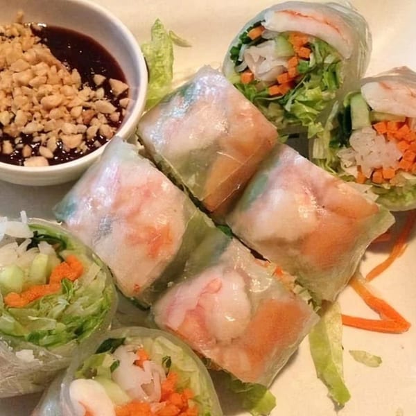 Fresh Thai spring rolls with shrimp, vegetables, and a side of peanut dipping sauce.
