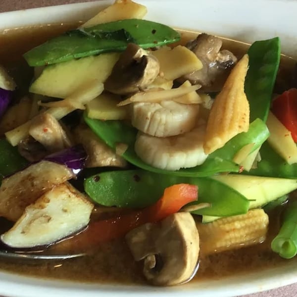 Close-up of a Thai Delight dish with snow peas, mushrooms, baby corn, and other vegetables in sauce.