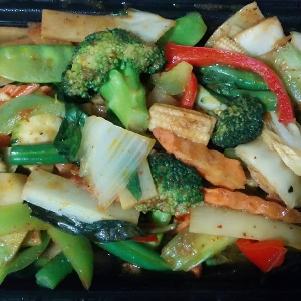 Close-up of a vibrant Thai stir-fry with broccoli, snap peas, carrots, and tofu.