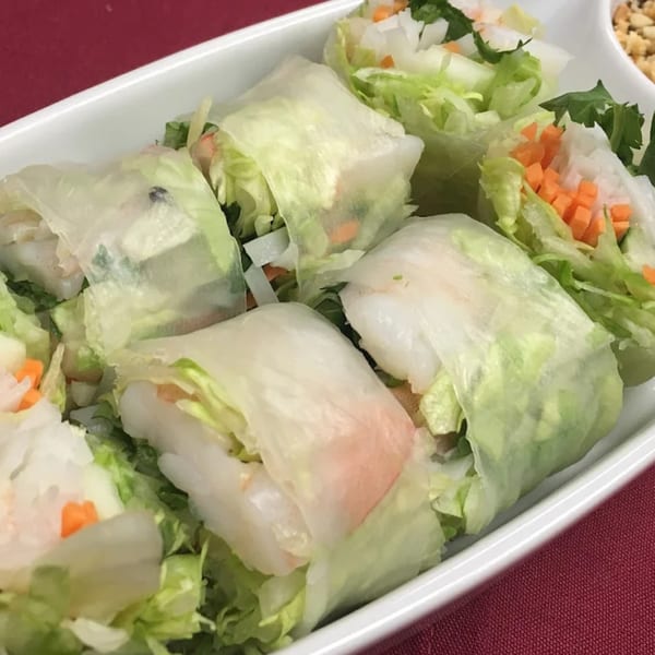 Fresh Thai spring rolls filled with shrimp, lettuce, and carrots, served in a white dish.
