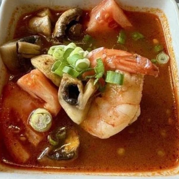 Spicy Thai Tom Yum soup with shrimp, mushrooms, tomatoes, and green onions.
